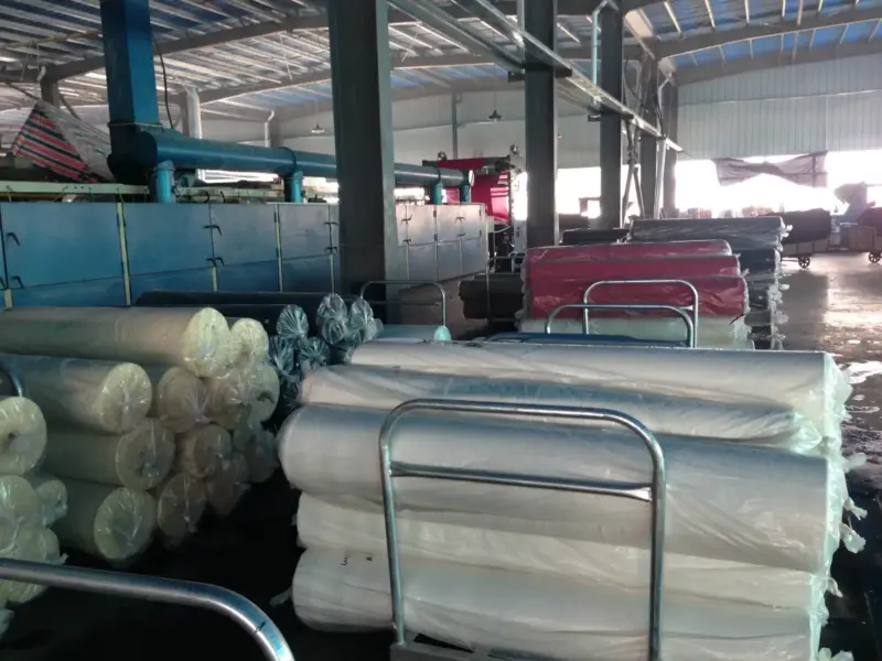 rolls of canvas fabric in a production warehouse, showcasing different weights and colors